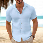 Men Short-Sleeved Button-Down Summer Shirt in light blue, worn by a man on the beach.