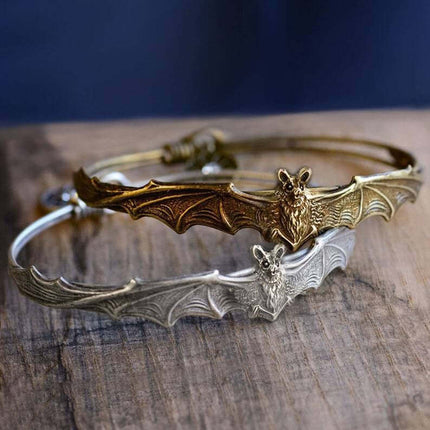 Creative Gothic Bat Charm Bracelet Halloween Jewelry with a gold and silver bat design on a wooden surface.