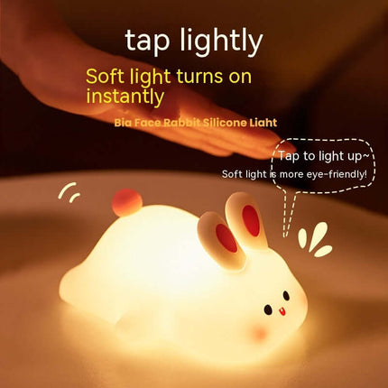 Cute Rabbit LED Night Light Soft Silicone Touch Lamp on a table with soft light turned on.