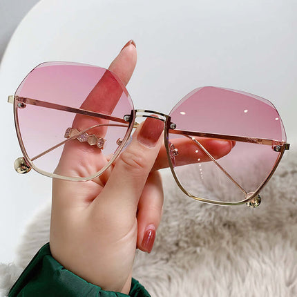 Elegant Fashion Sunglasses for a Slimming Face Look held in a hand with pink lenses and gold frames