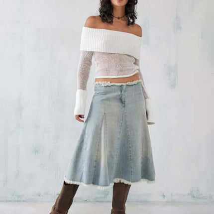Model wearing an off shoulder long sleeve knit top slim stretch with a denim skirt and brown boots.