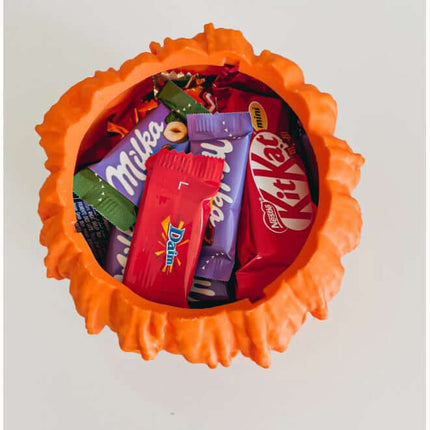 Top view of Halloween Melting Pumpkin Candy Bowl With Lid filled with candies like Milka and Kit Kat.