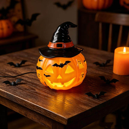 Halloween Night Light USB Powered Pumpkin Lamp with witch hat on a wooden table surrounded by bats and a candle.
