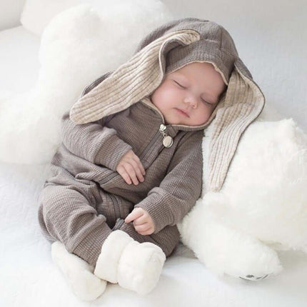 Baby wearing a Rabbit Ears Baby Romper cotton blend hooded jumpsuit, peacefully sleeping next to a soft plush bear.