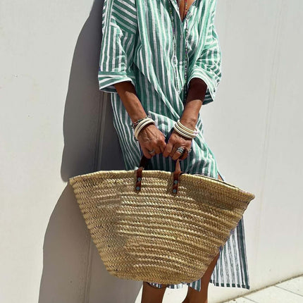 Woman wearing a Striped Half-Sleeve Belted Lapel Shirt Dress, holding a straw bag, against a light wall.