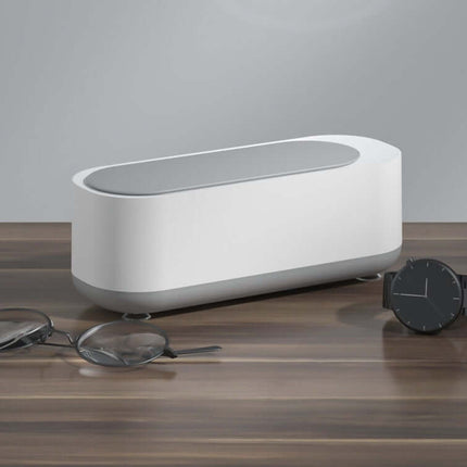 Ultrasonic High Frequency Jewelry and Glasses Cleaner on a wooden table with glasses and a watch.