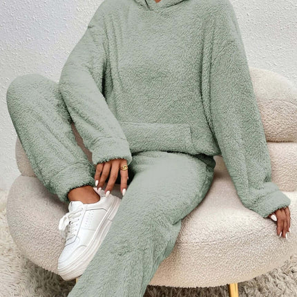 Winter Plush Pajama Set Fashion Hooded Top and Pants in soft green cozy fabric on a model seated on a chair.