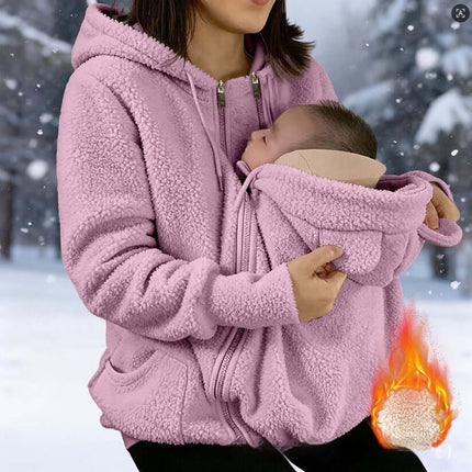 Womens Corduroy Hooded Jacket With Baby Pocket in pink worn by a woman holding a baby in snowy background.