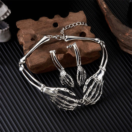 Womens Dark Gothic Skeleton Hand Necklace Earrings Set displayed on a wooden surface, featuring intricate skeleton hand designs.