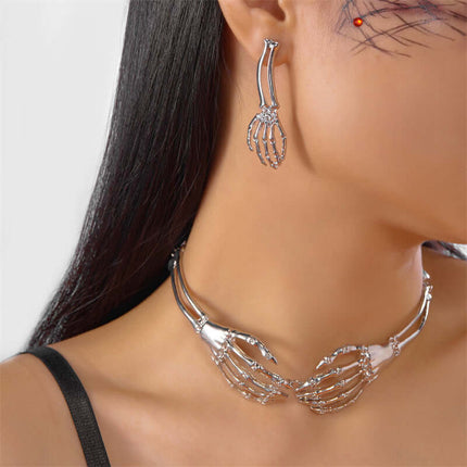 Womens Dark Gothic Skeleton Hand Necklace Earrings Set worn by a model with dark hair and intricate accessories.