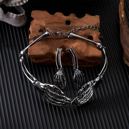 Womens Dark Gothic Skeleton Hand Necklace Earrings Set displayed on wooden surface with dark background.