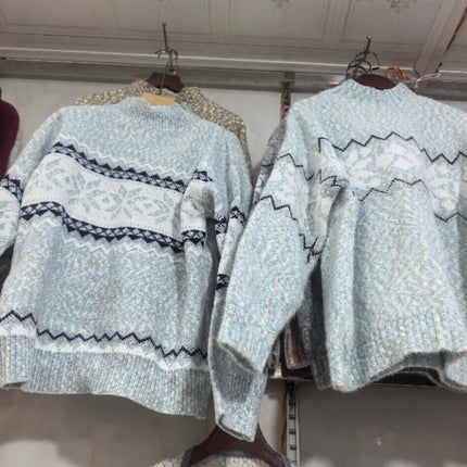 Women's Winter Snowflake Half Turtleneck Sweater displayed on hangers with intricate blue patterns.